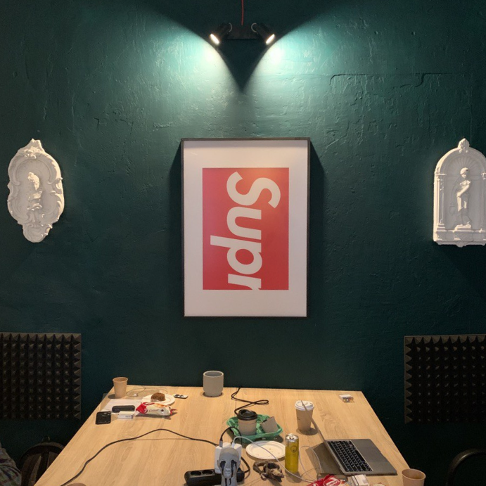 Emerald colored wall with Supreme poster on it.